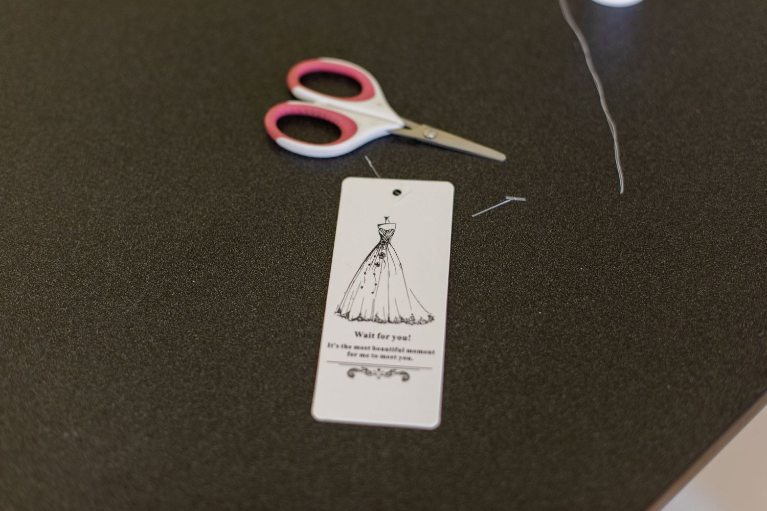 Wedding dress tags and scissors on a dark background.