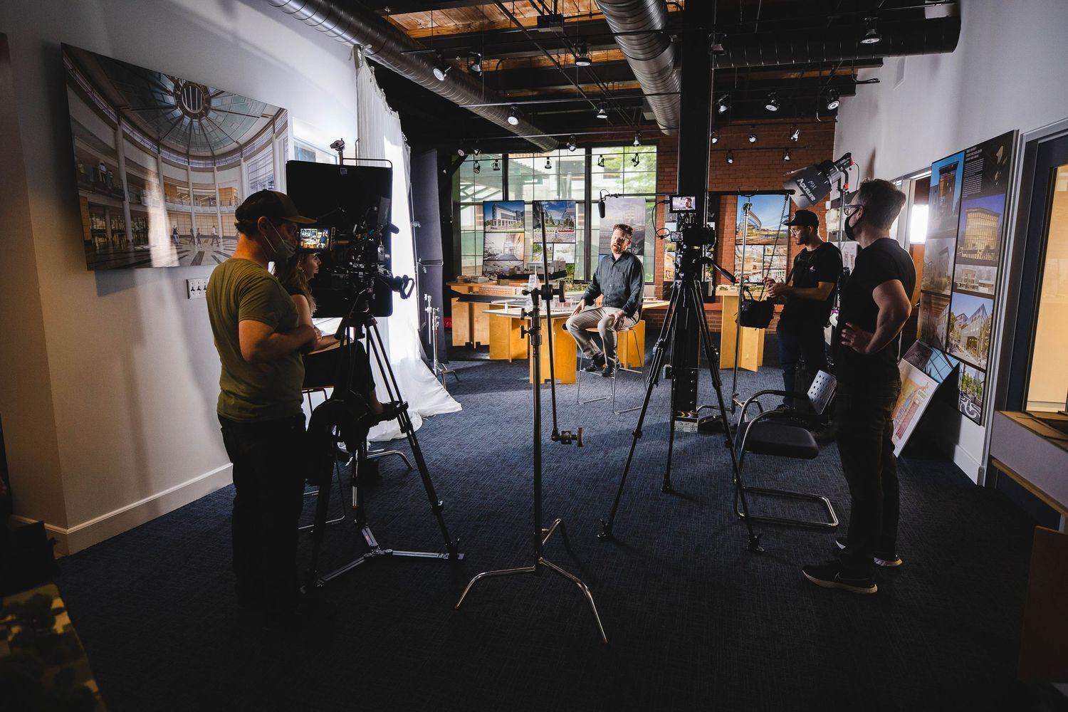 Multiple camera operators filming in a dimly lit studio space with professional equipment.