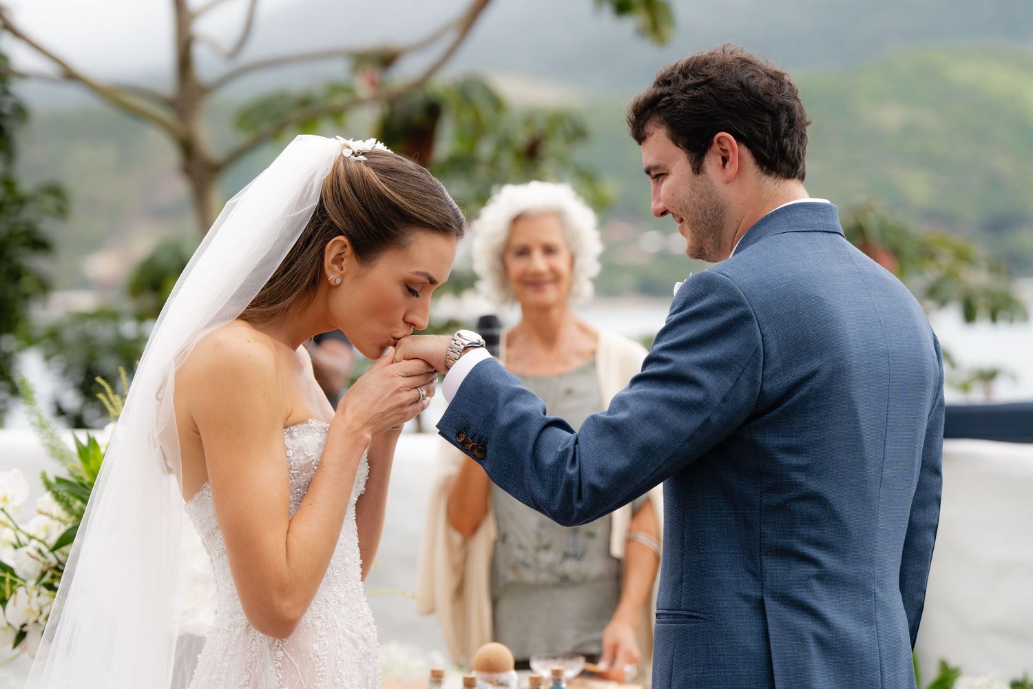 Happy couple shares intimate moment during ring exchange at scenic outdoor wedding.