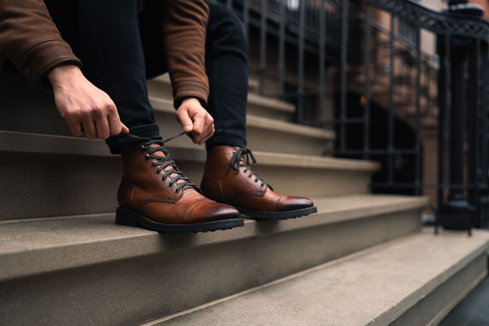 Close-up view of brown leather dress shoes on concrete steps in an urban setting.