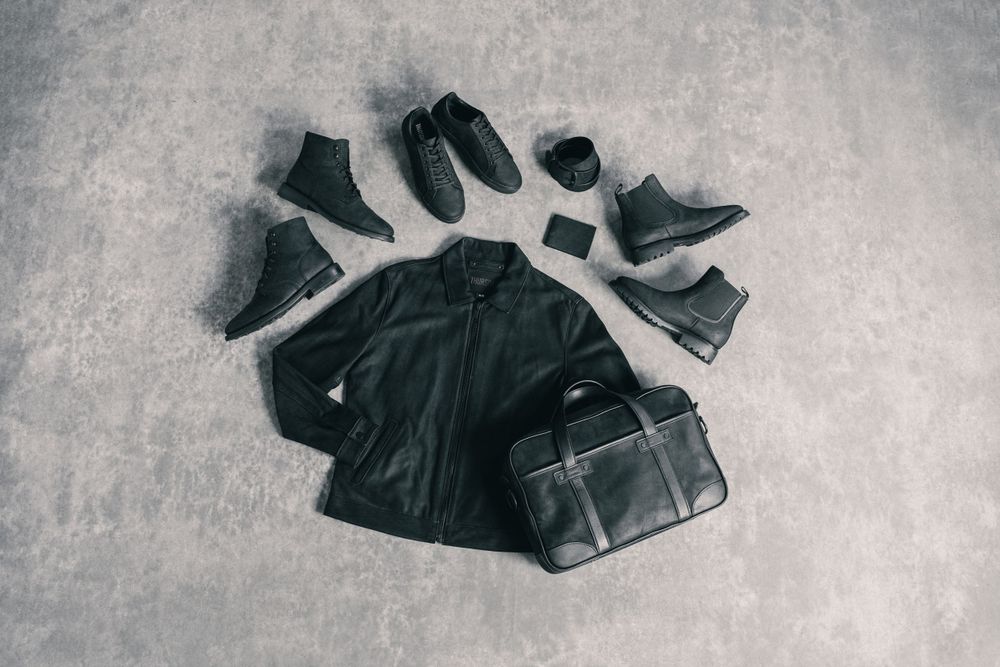 Collection of black leather shoes and boots arranged on grey textured background.