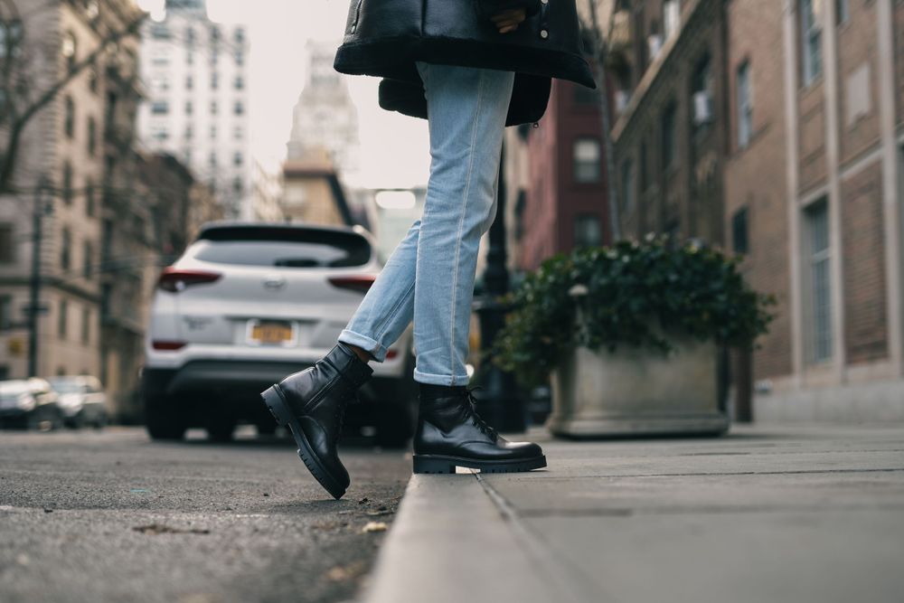 Urban street scene with light blue jeans and shoes walking on pavement.