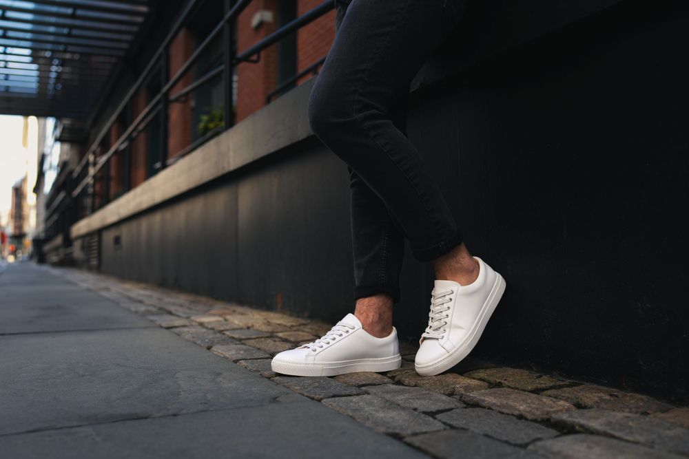 White sneakers against dark urban background on concrete surface.