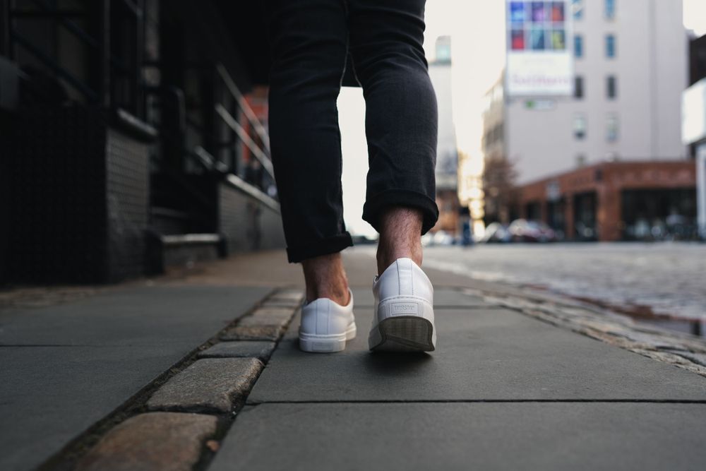 Low angle shot of feet walking on urban sidewalk grates.