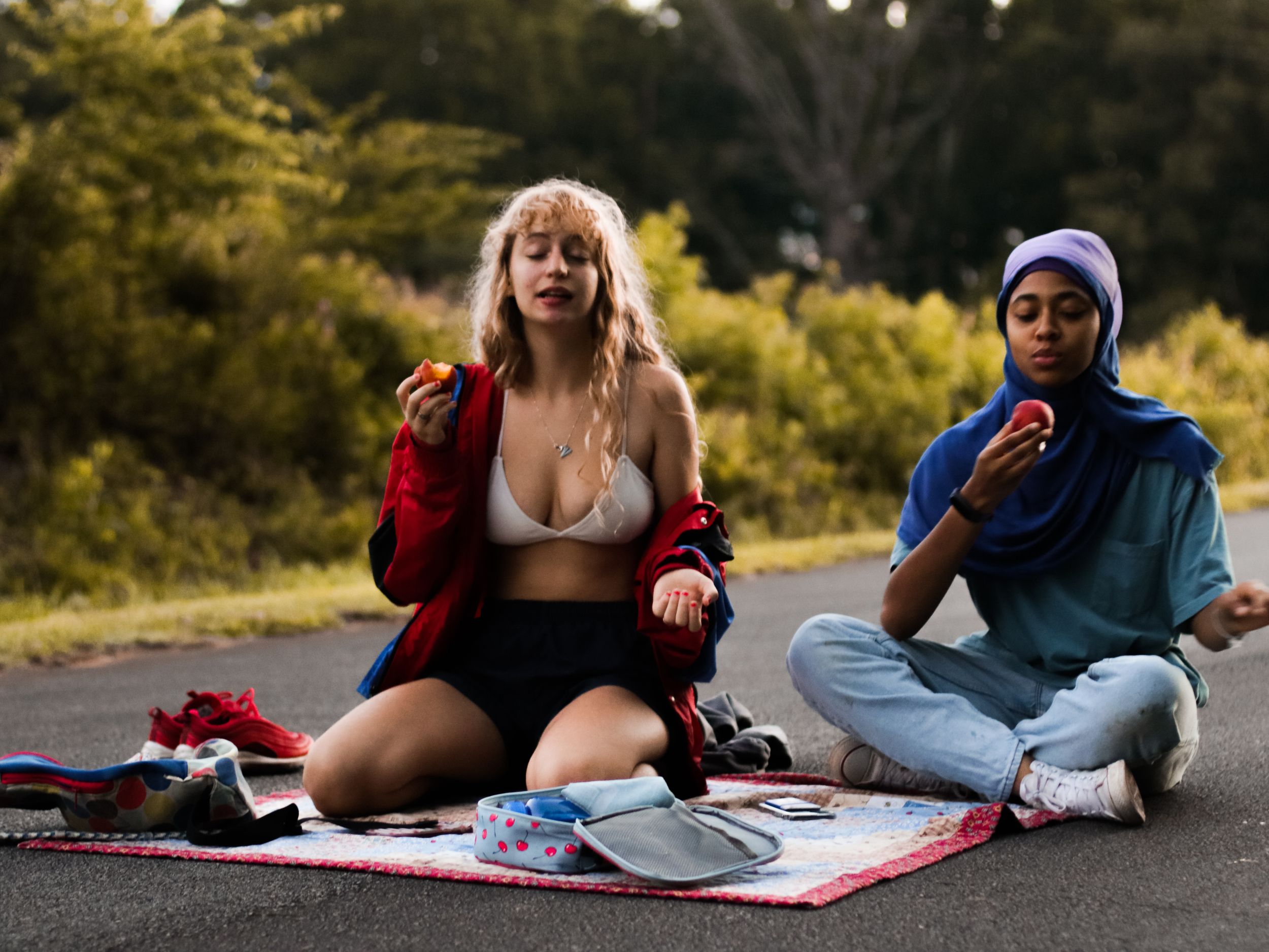 Two people relax together on a blanket outdoors during golden hour.