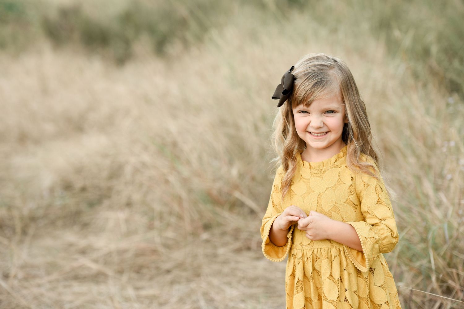 Family and children photography in a grassy field little girl with flowers