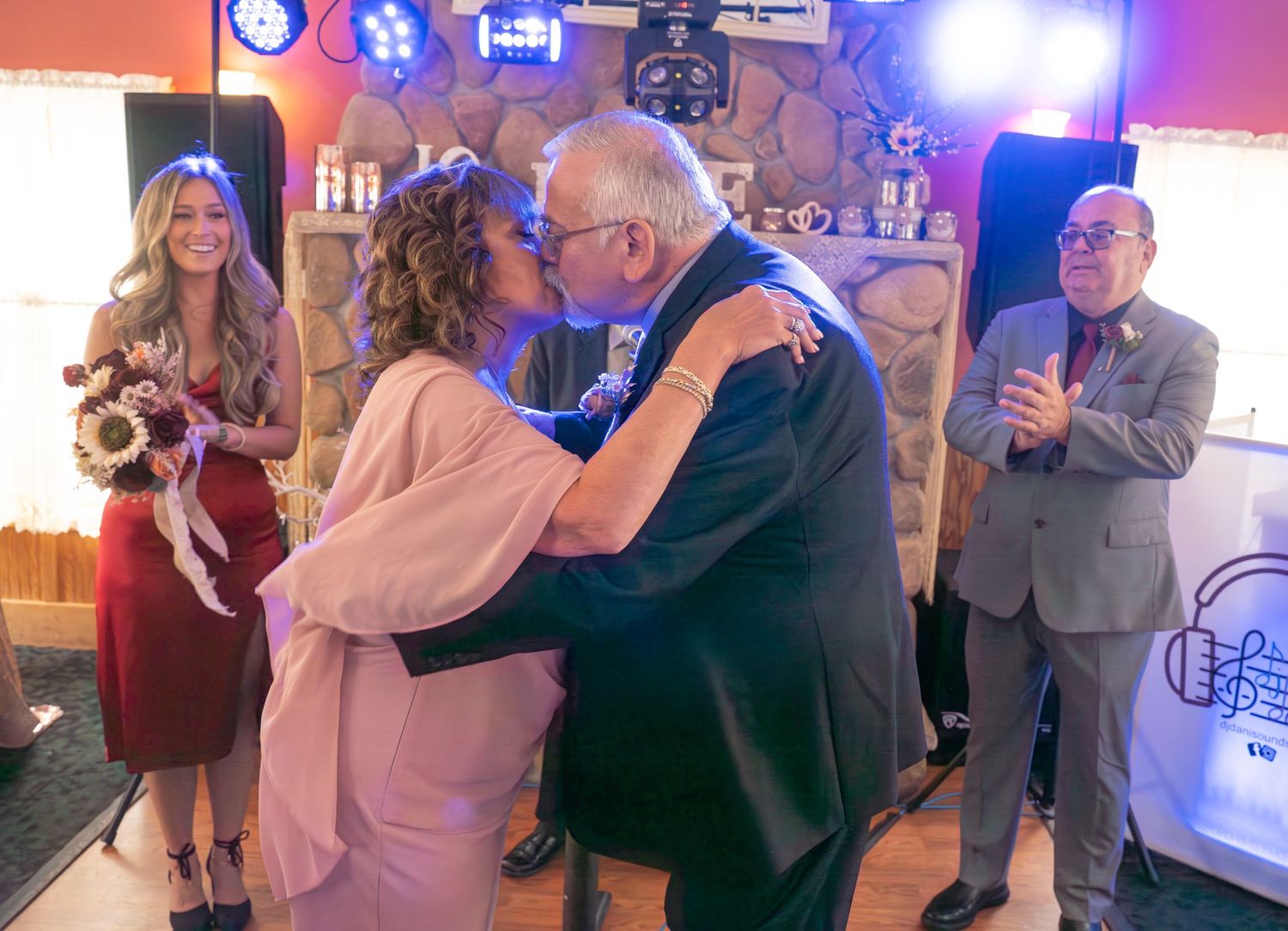 Couple dances together at reception venue with blue stage lighting.