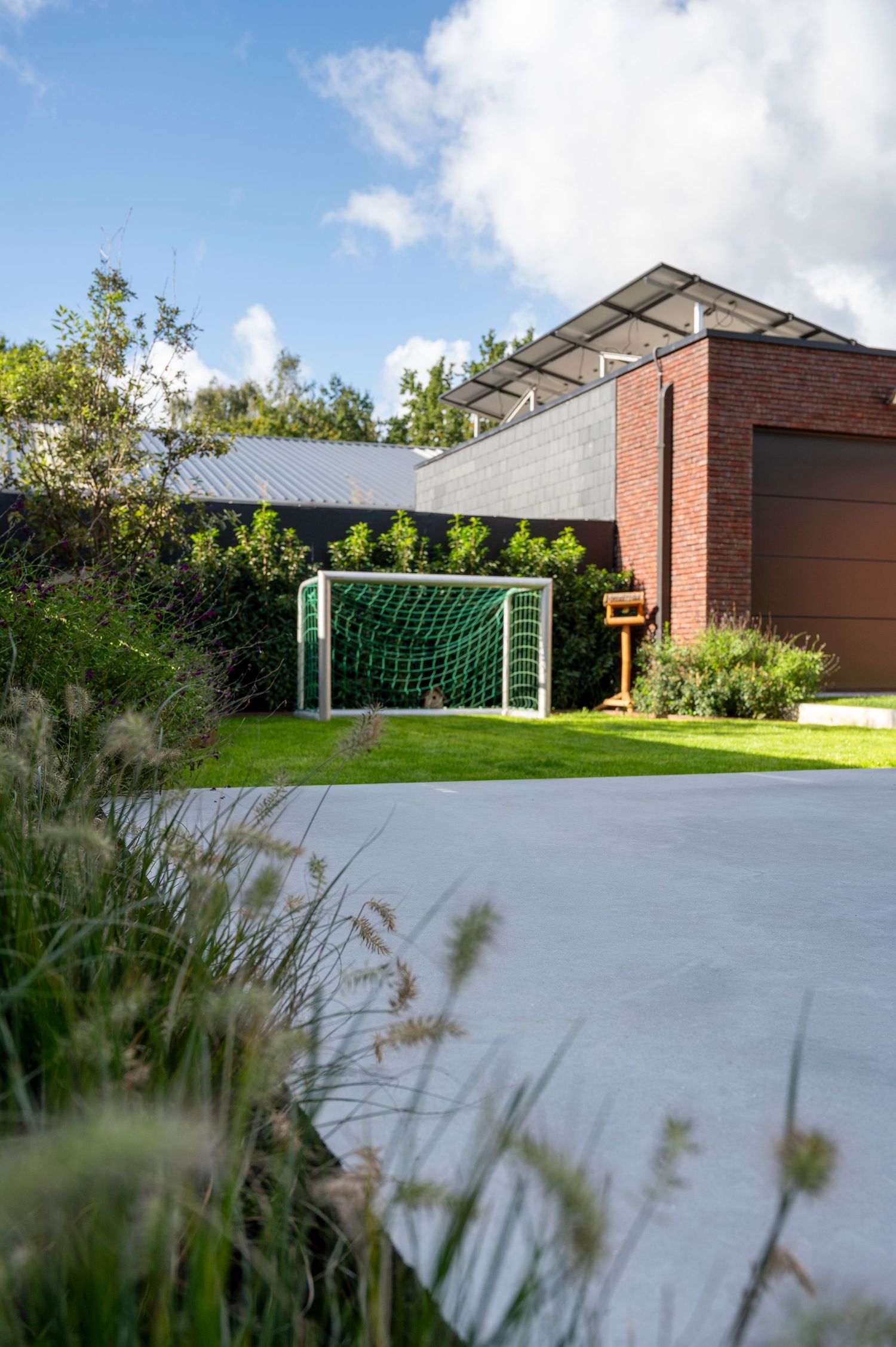 Soccer goals on a concrete court with red brick building and green lawn in the background.