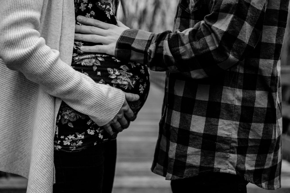 Close-up shot of hands touching a floral patterned dress and plaid shirt in black and white.