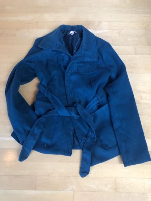 Navy blue belted jacket with pockets and lapels laid flat.