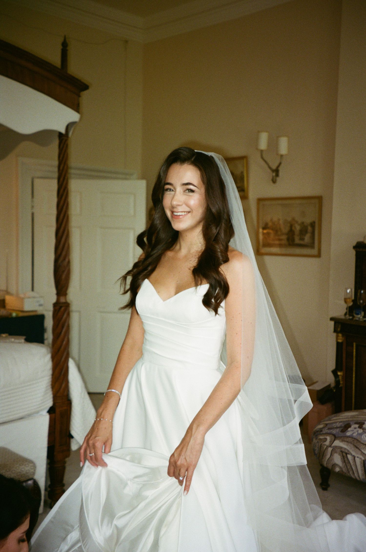 A bride in a classic white wedding dress and veil poses in an elegant room.