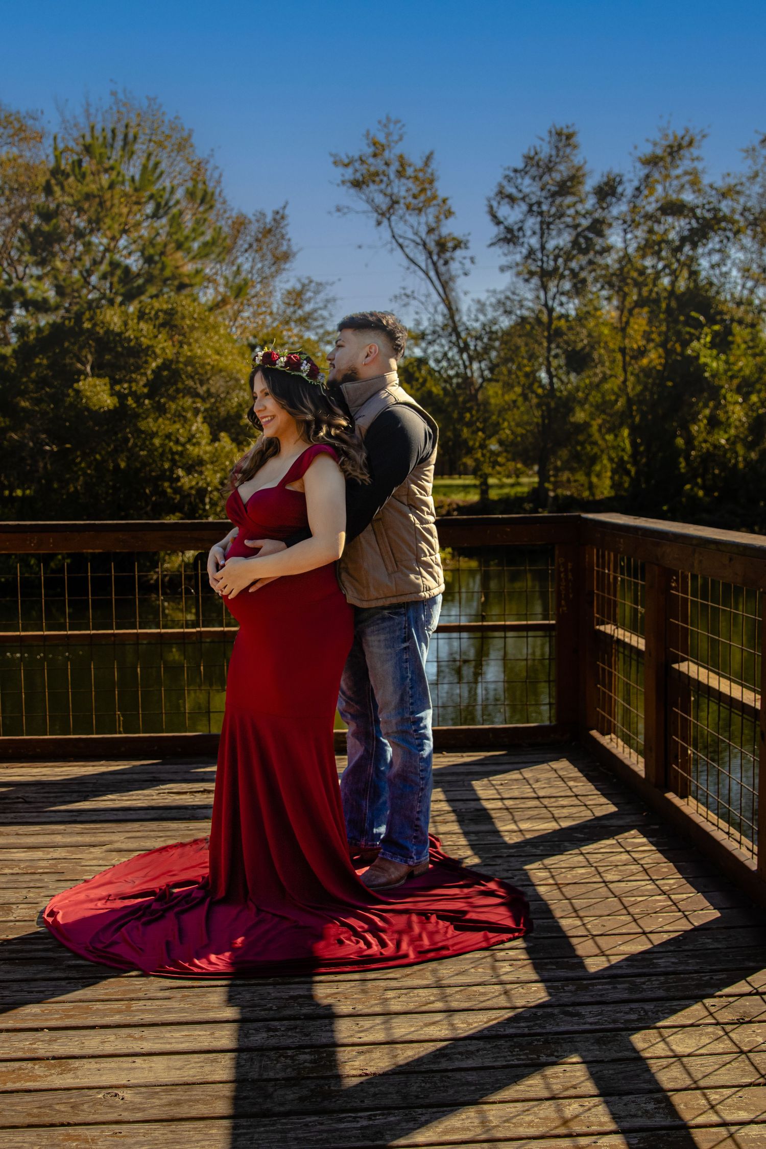 Romantic sunset photoshoot on a wooden boardwalk overlooking a serene lake with autumn trees in the background.
