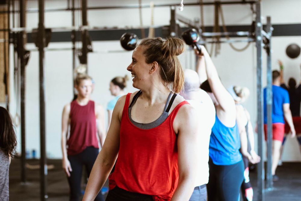 Athletes working out in a CrossFit gym with equipment and fellow members.