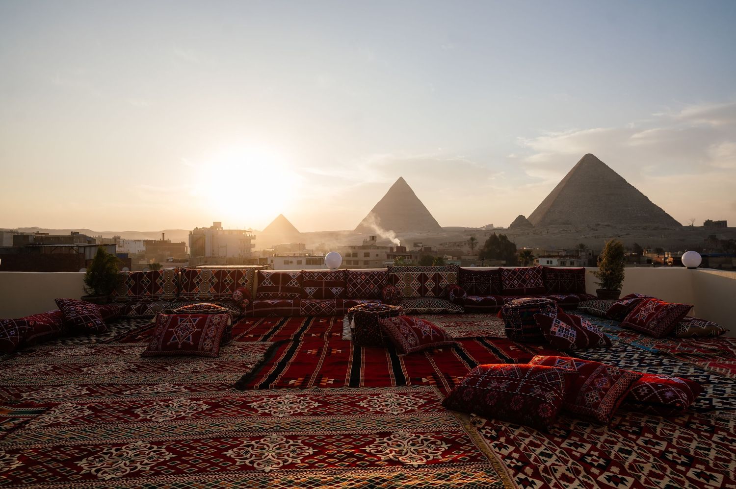 Sunset view of the Egyptian pyramids with traditional carpets laid out in the foreground.