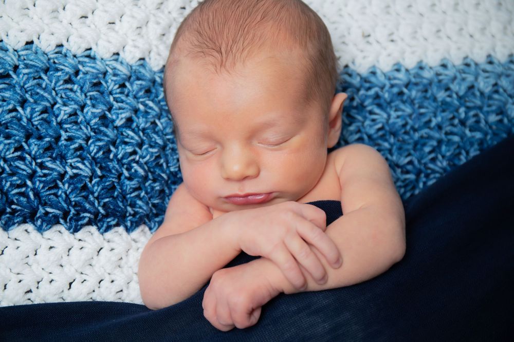 Sleeping baby on blue and white striped knit blanket.
