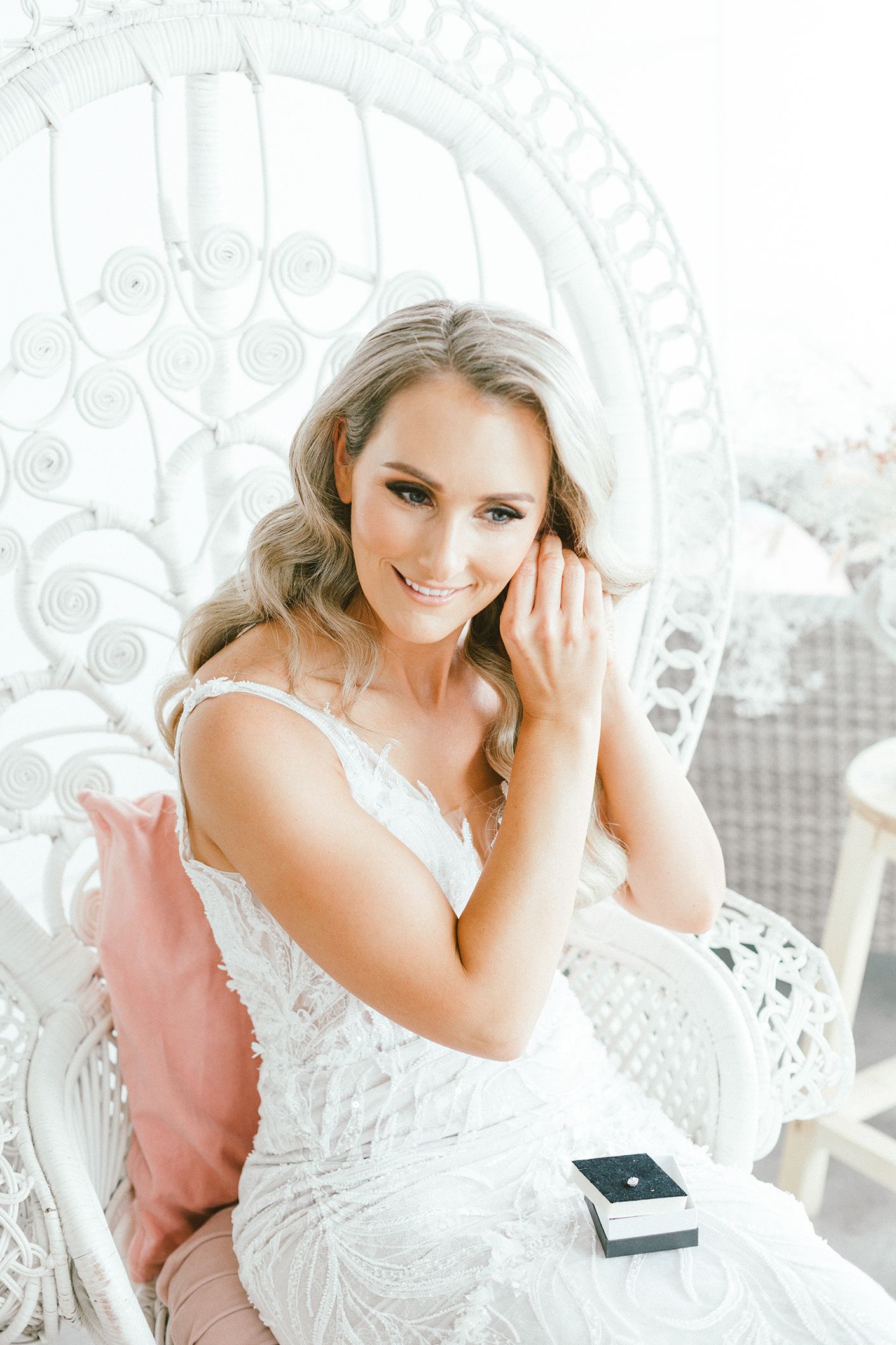 A stunning wedding dress against a decorative white wicker peacock chair backdrop.