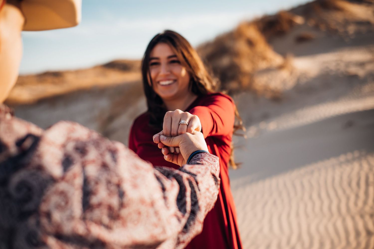 A maternity photoshoot at sunset in a desert landscape with sand dunes.