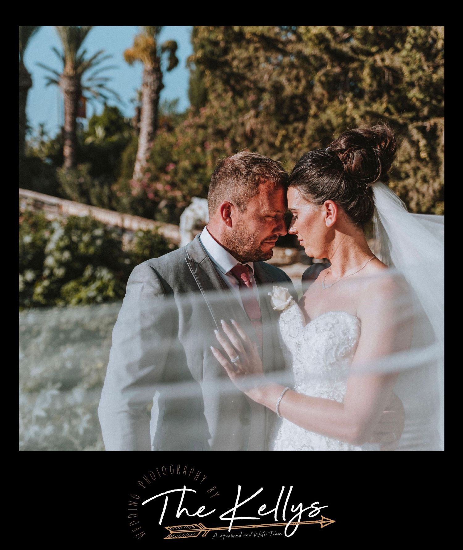 A romantic wedding portrait of a couple embracing beneath palm trees during golden hour.