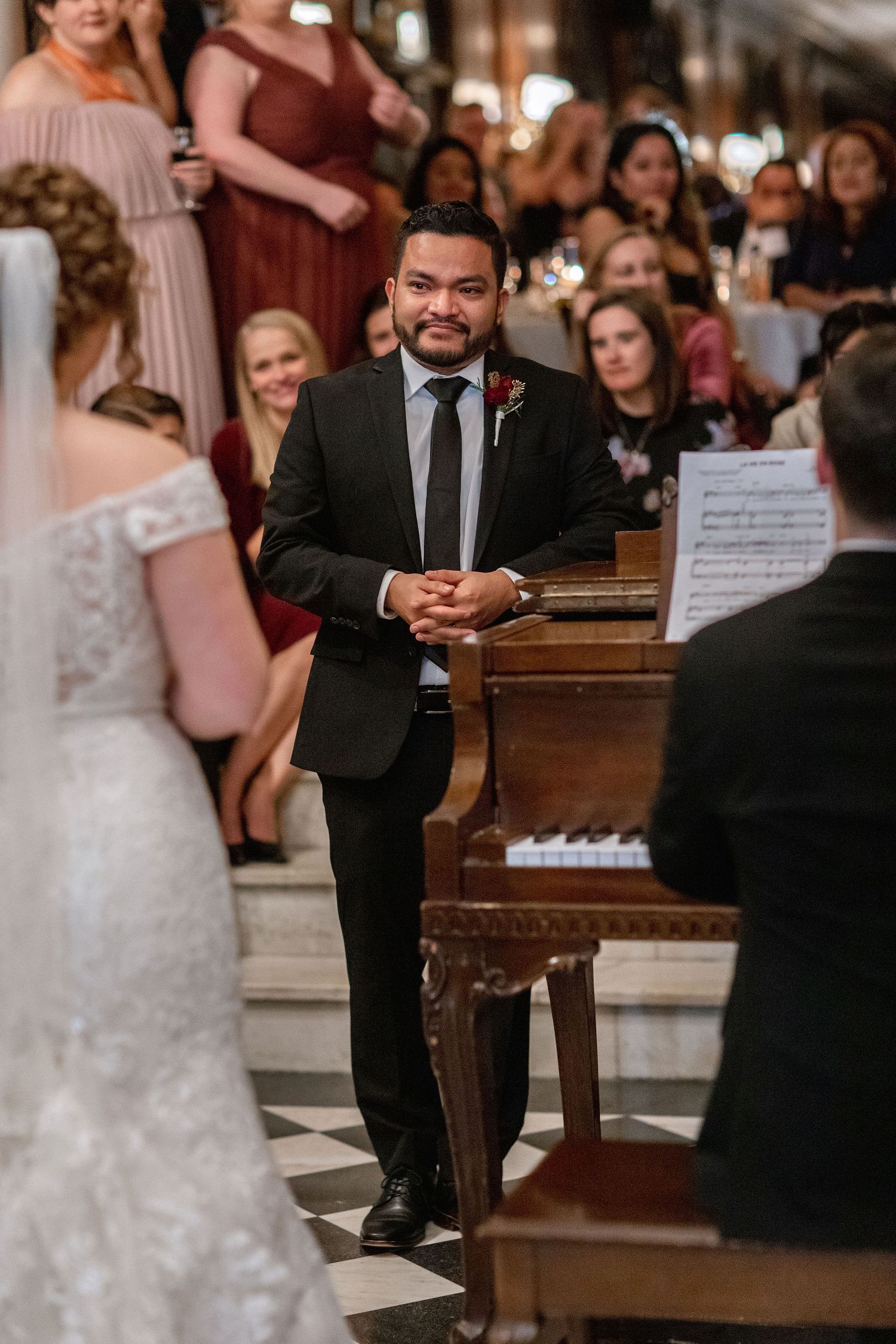 Wedding celebration scene with formal attire and piano music in an elegant indoor setting.