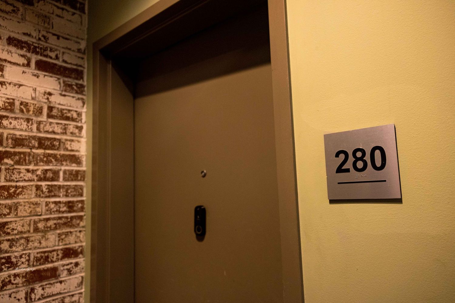 Room number 280 displayed on beige wall next to dark doorway with exposed brick detail.