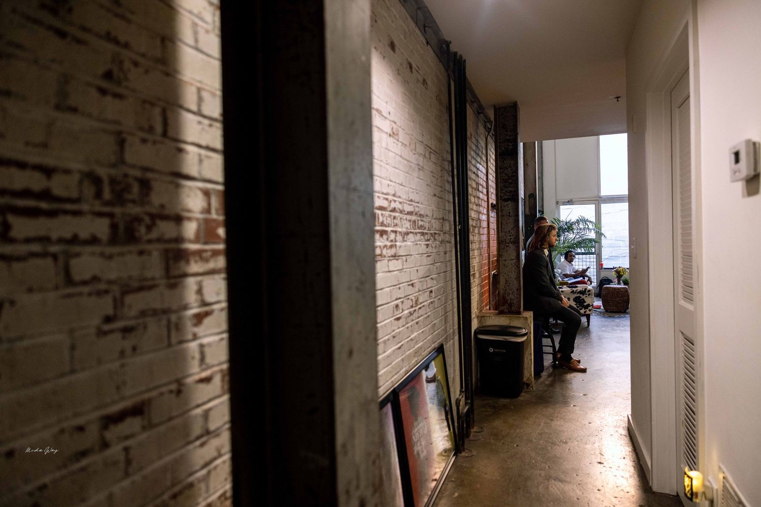 Long narrow hallway with exposed brick walls and industrial style lighting.