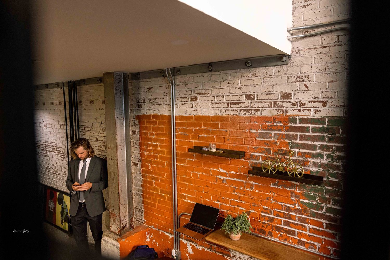 Person standing against orange and gray brick wall in modern office space.