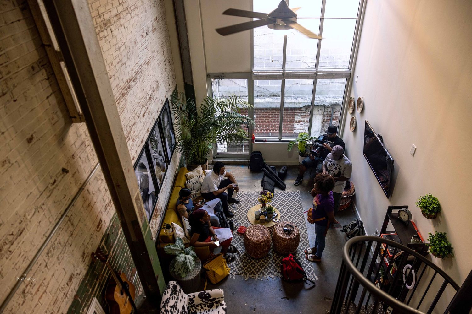 View from above of people meeting in an industrial-style space with exposed brick walls.