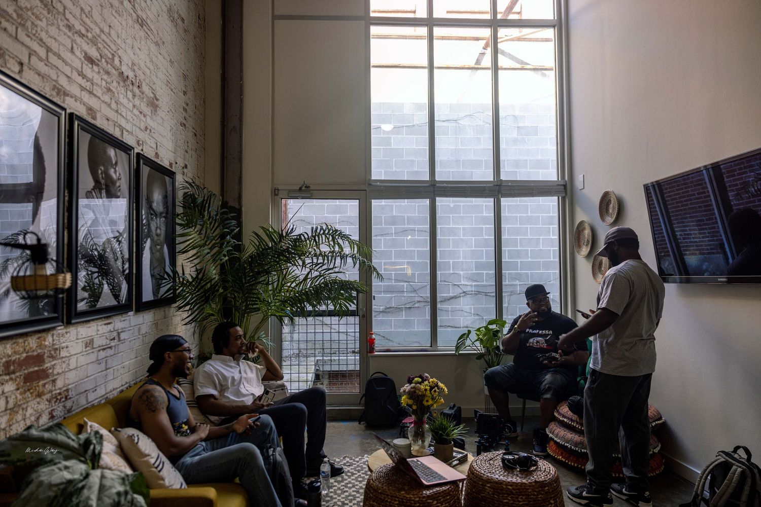 Group gathering in modern loft space with large windows and brick walls.