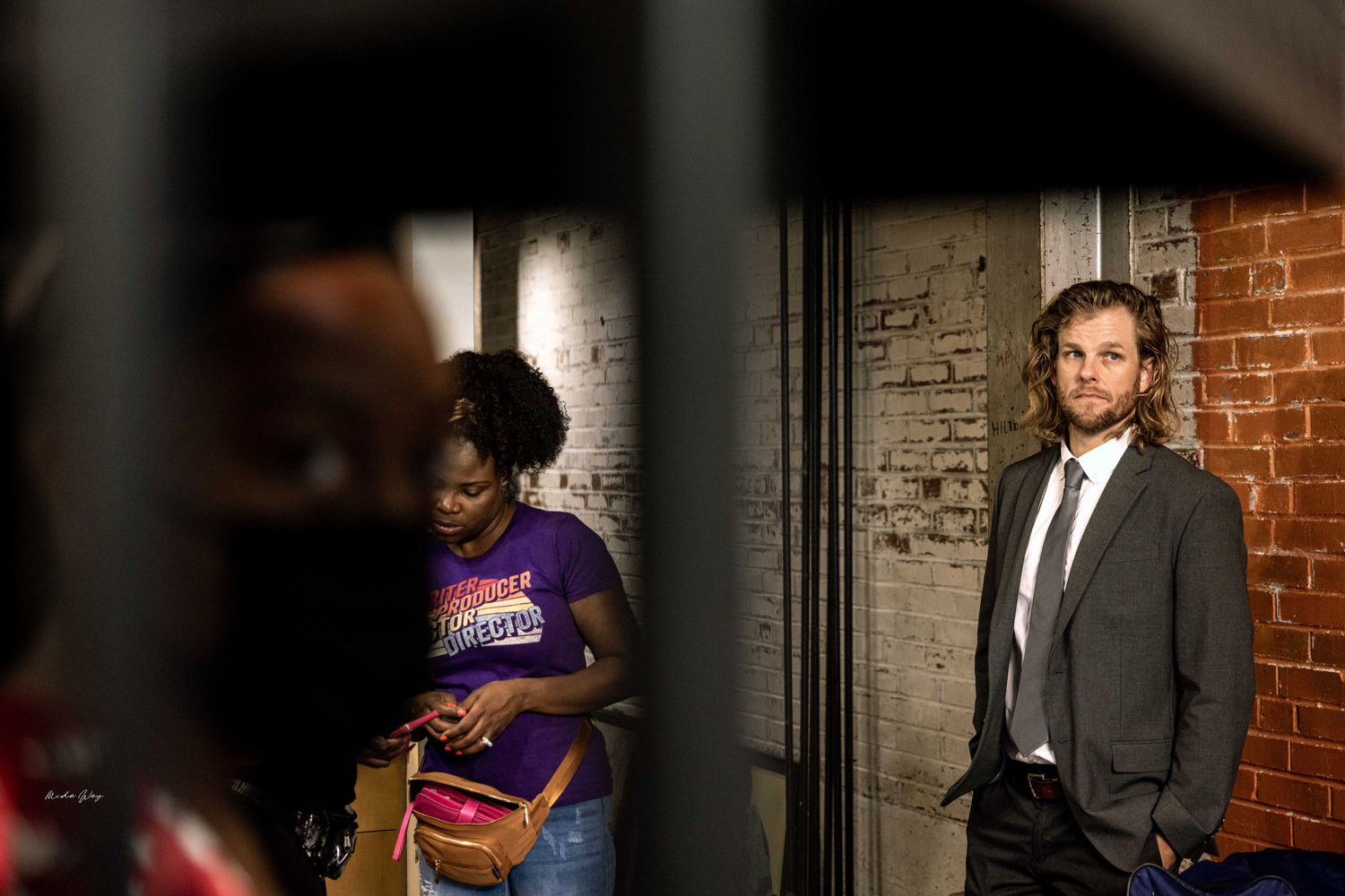 Two people standing in an industrial-style room with exposed brick walls.