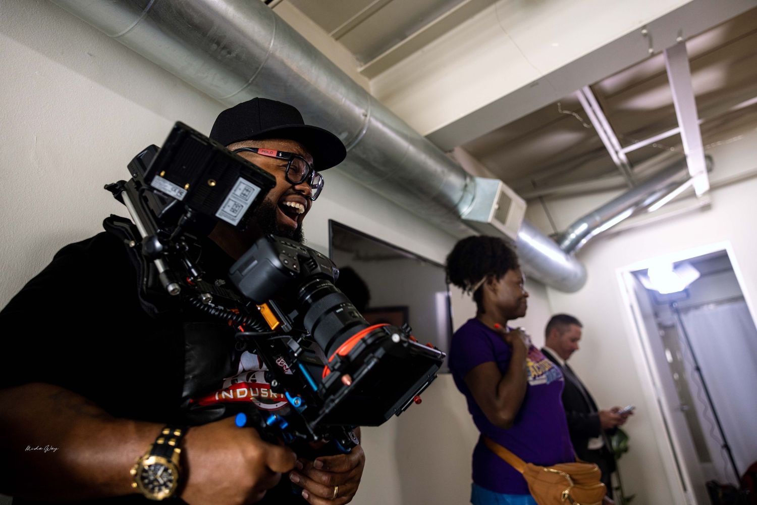 Camera operator filming with professional equipment in an industrial hallway.