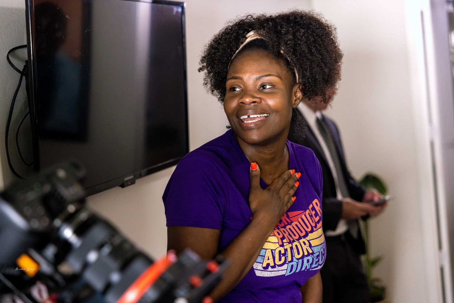 Someone in a purple shirt smiling during what appears to be a video production.