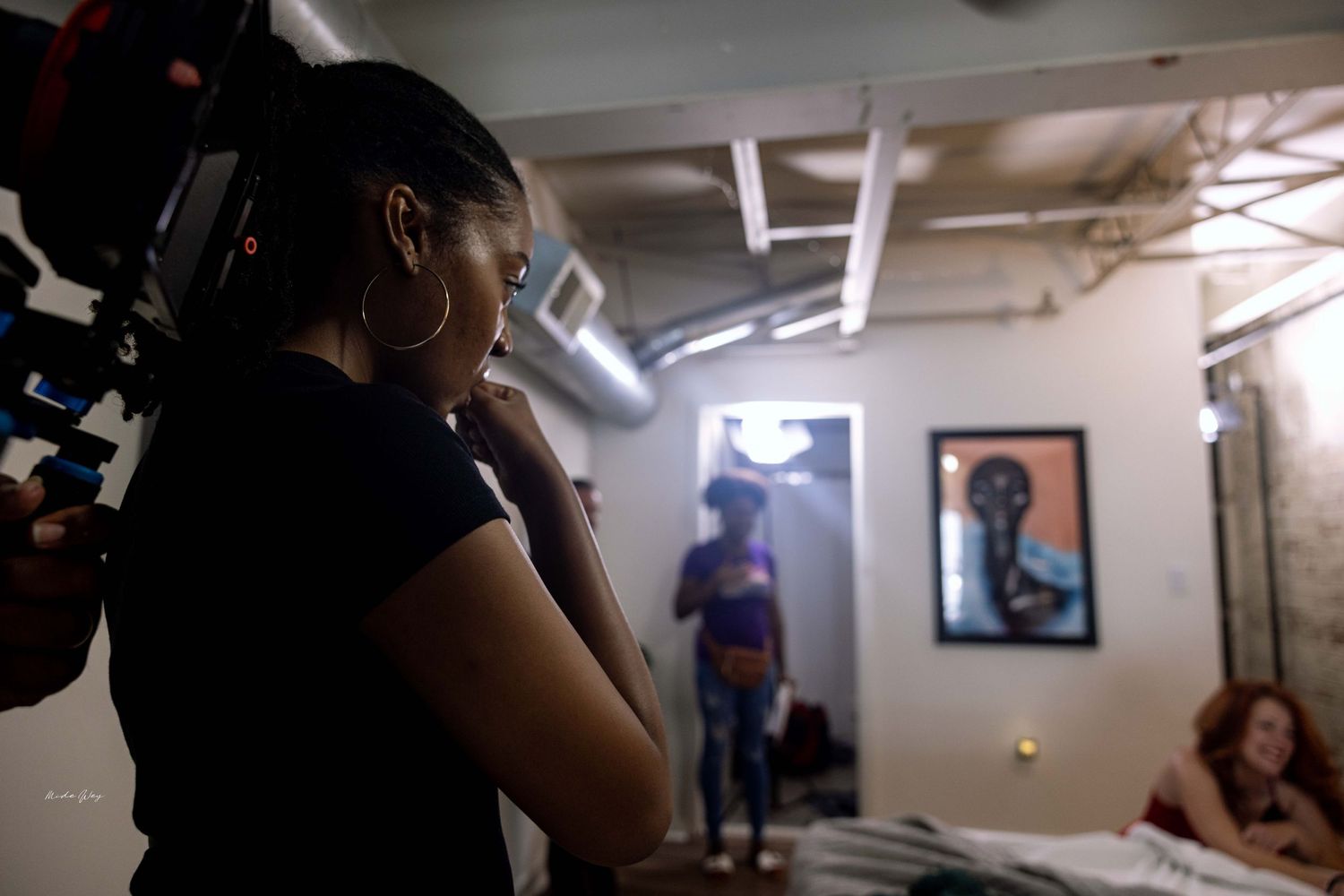 Film crew member watches scene through camera monitor.
