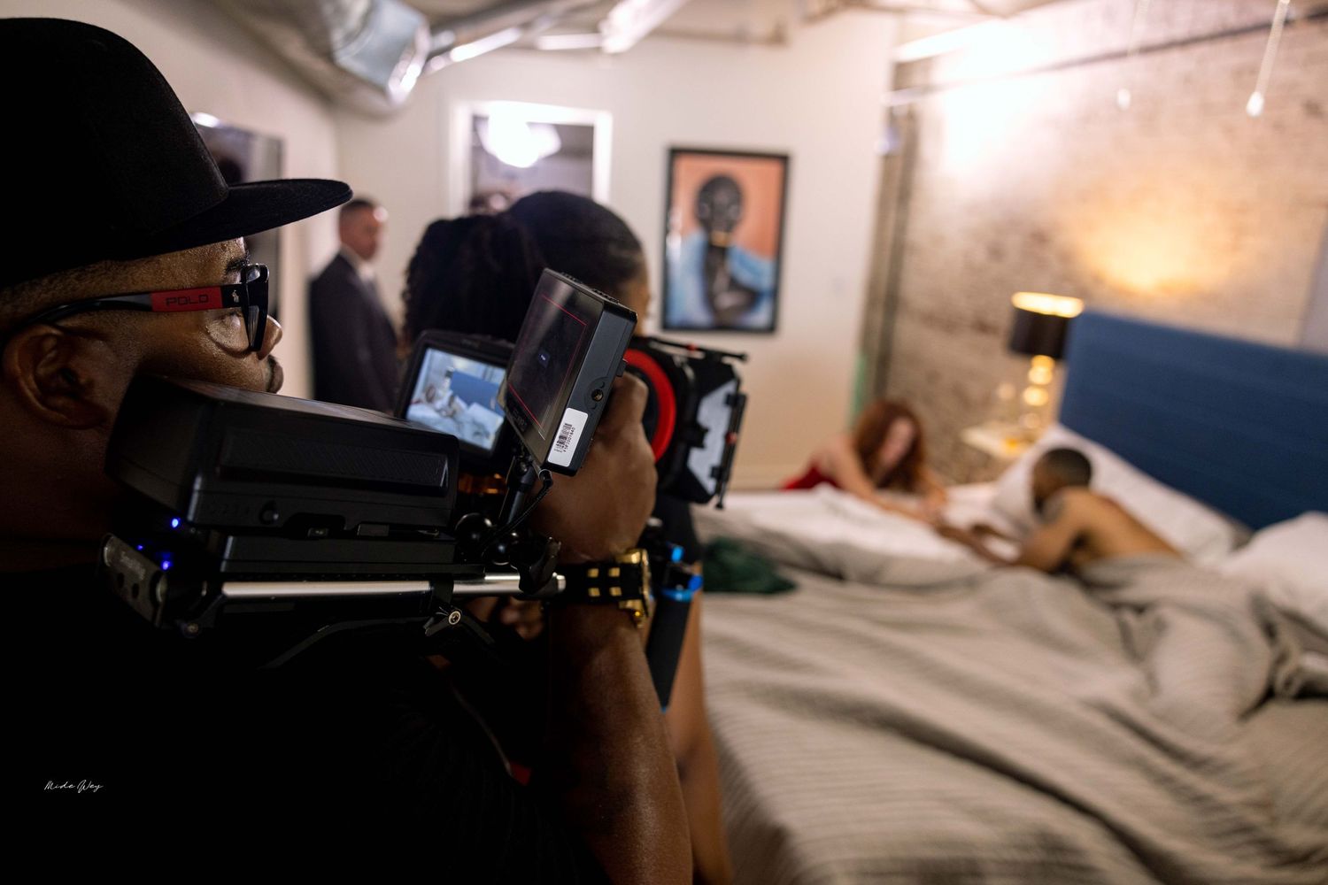 Camera operator films scene through professional equipment in studio setting.