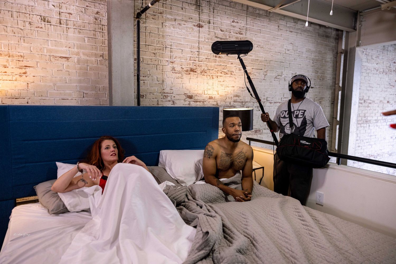 Behind the scenes film crew shooting bedroom scene with microphone boom.