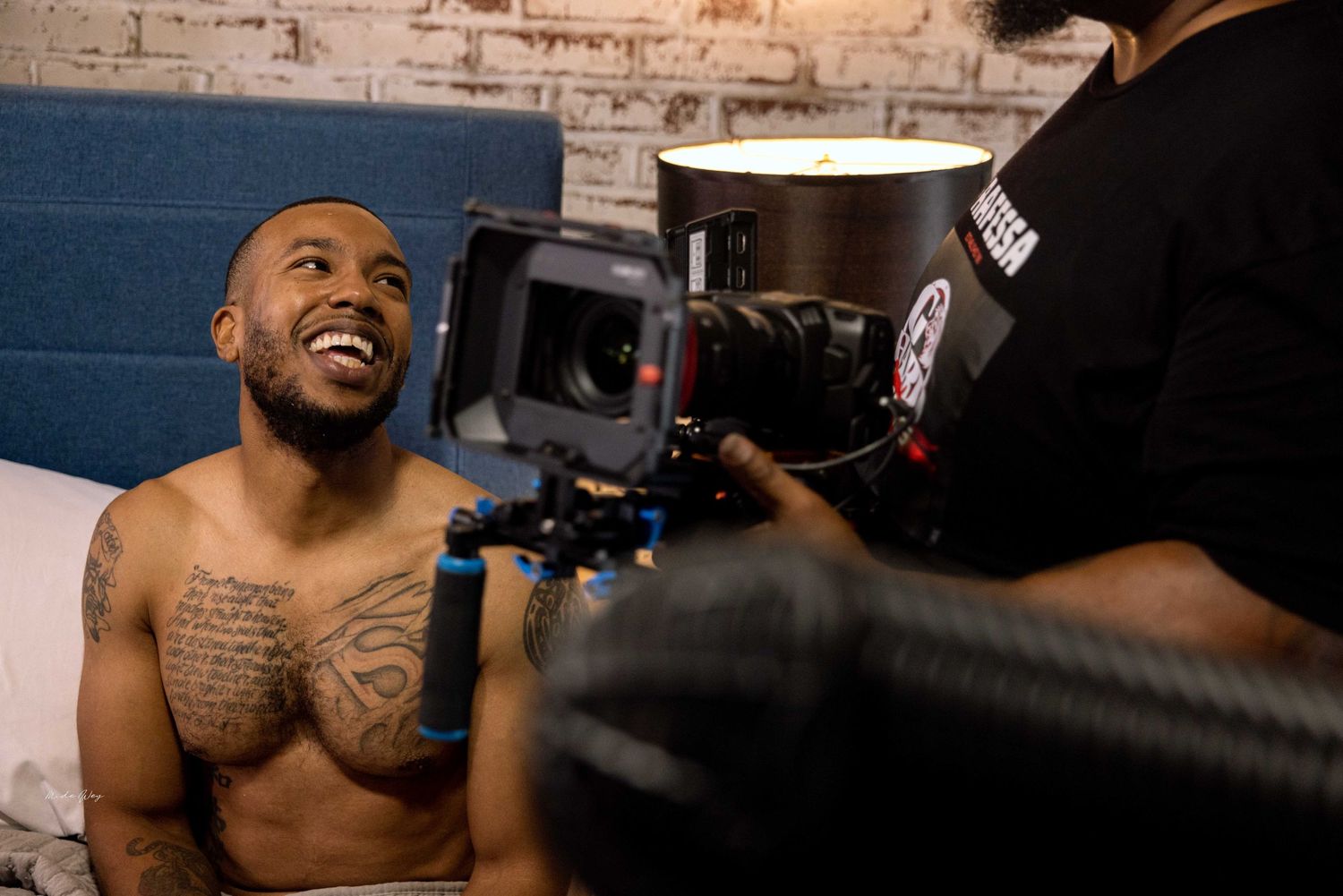 Film production crew working with camera equipment in a brick-walled studio.