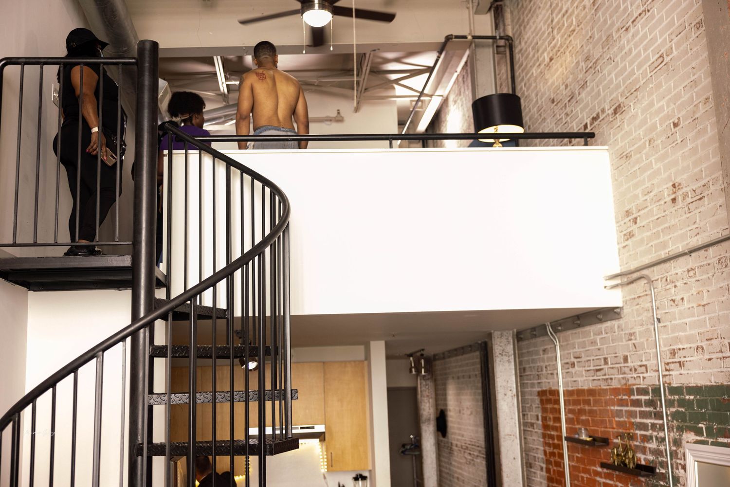 Industrial loft space with exposed brick walls and spiral metal staircase.