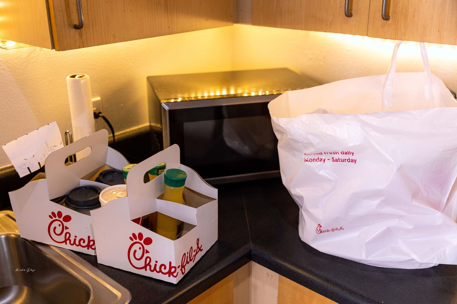 Fast food takeout bags from Chick-fil-A arranged on a kitchen counter.