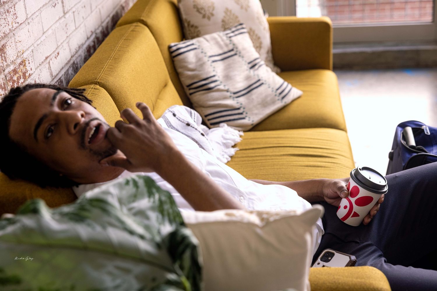 Relaxed scene of someone lounging on a yellow couch while using a phone.