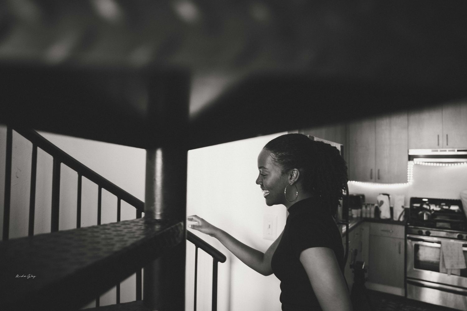 Side profile silhouette of someone on a staircase near a kitchen area in black and white.