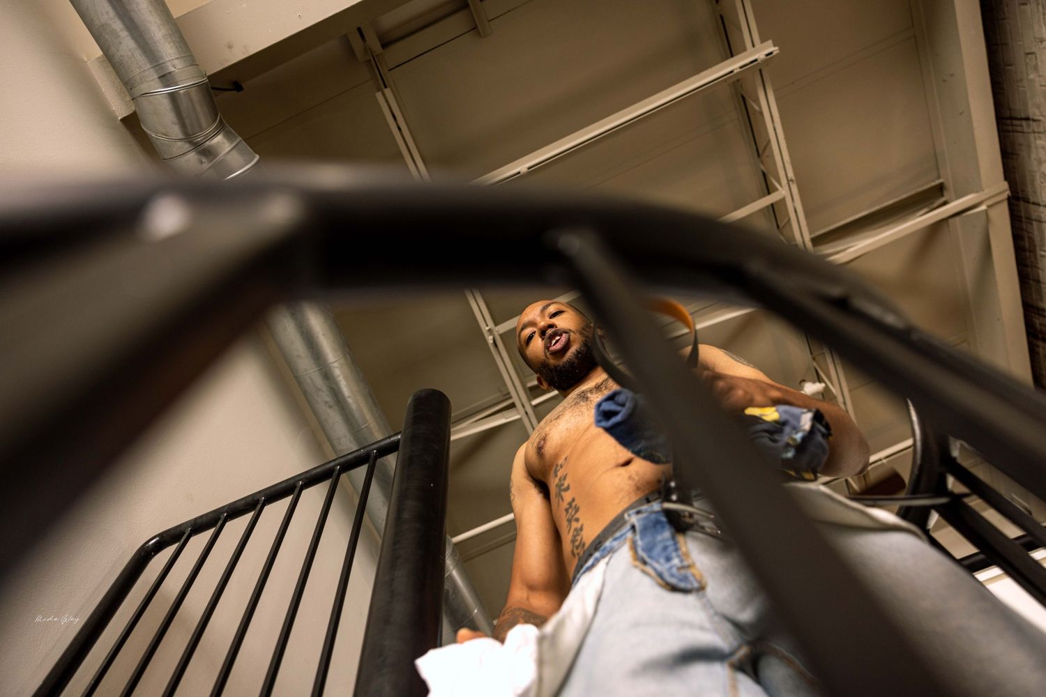 Low angle view of someone ascending a black metal staircase in an industrial space.