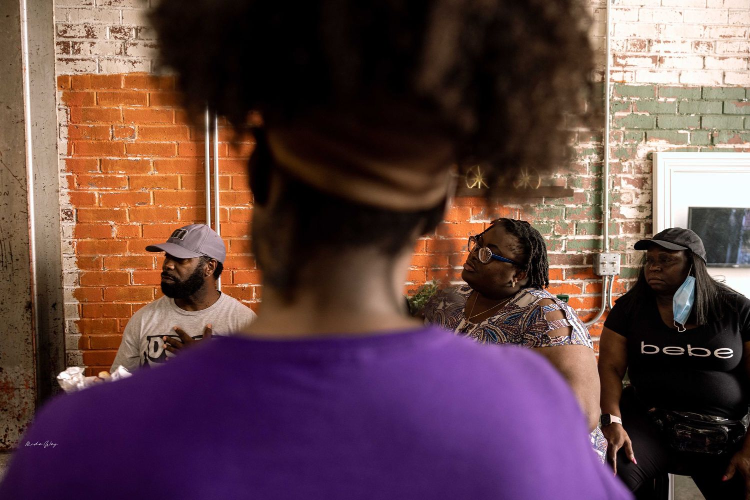 A gathering of people in a casual indoor setting with exposed brick walls.