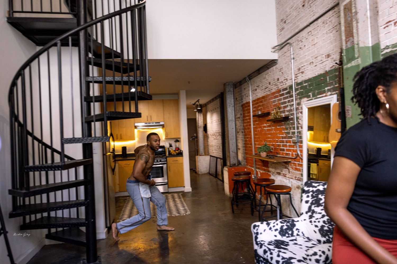 Modern industrial space with spiral staircase, exposed brick walls, and vintage photographs.
