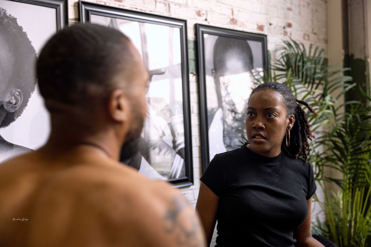 Two people engaged in conversation against a backdrop of black and white portrait photography.