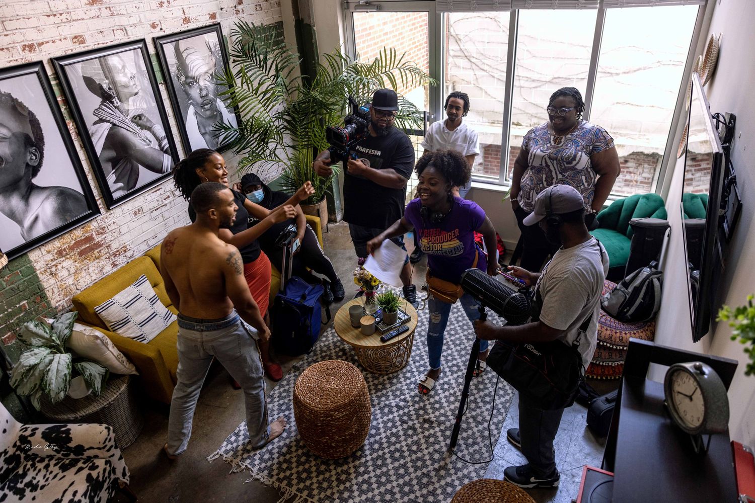 People gathered in a loft-style room with potted plants and black and white photographs on the walls.