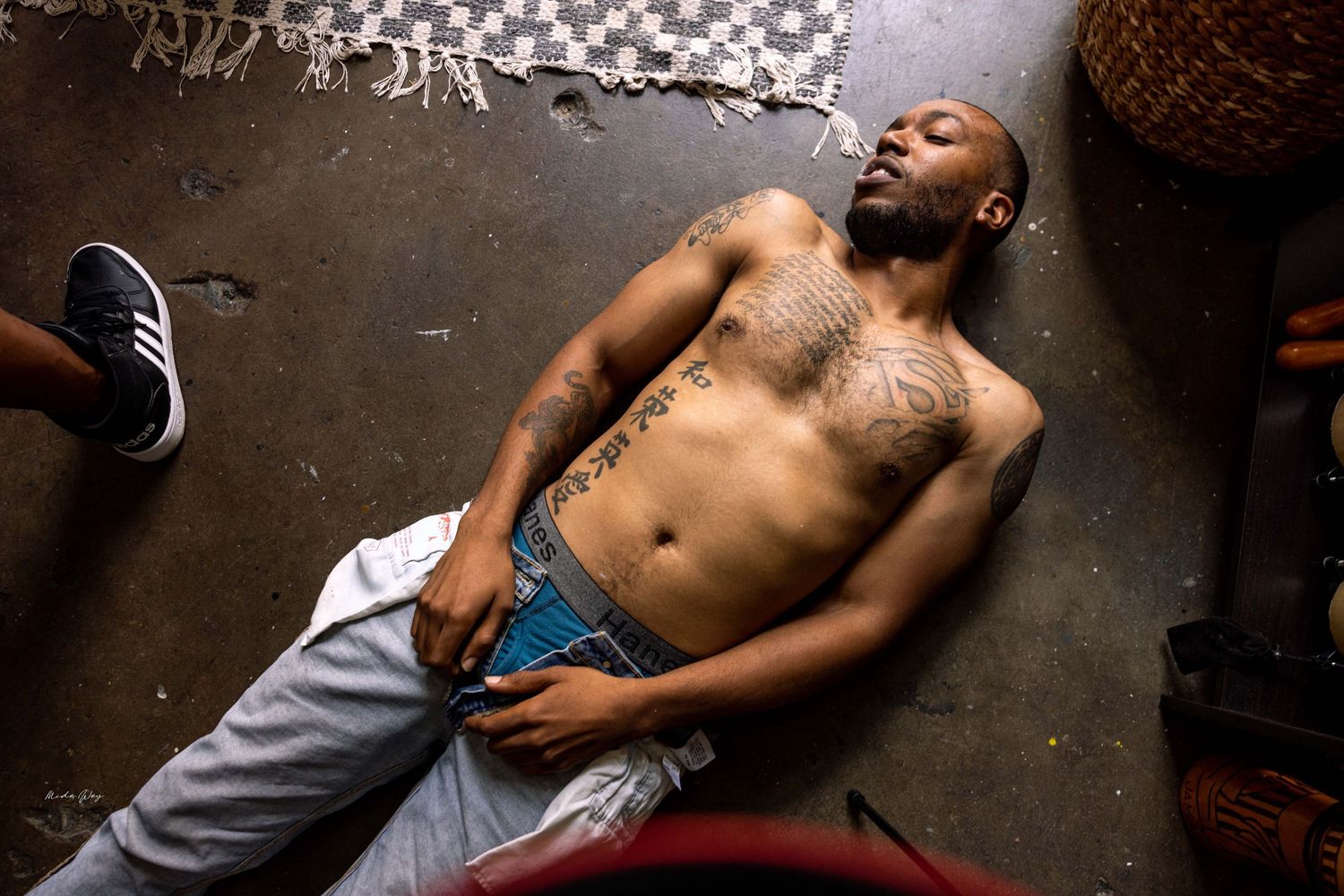 Overhead shot of a shirtless person reclining on a patterned floor.