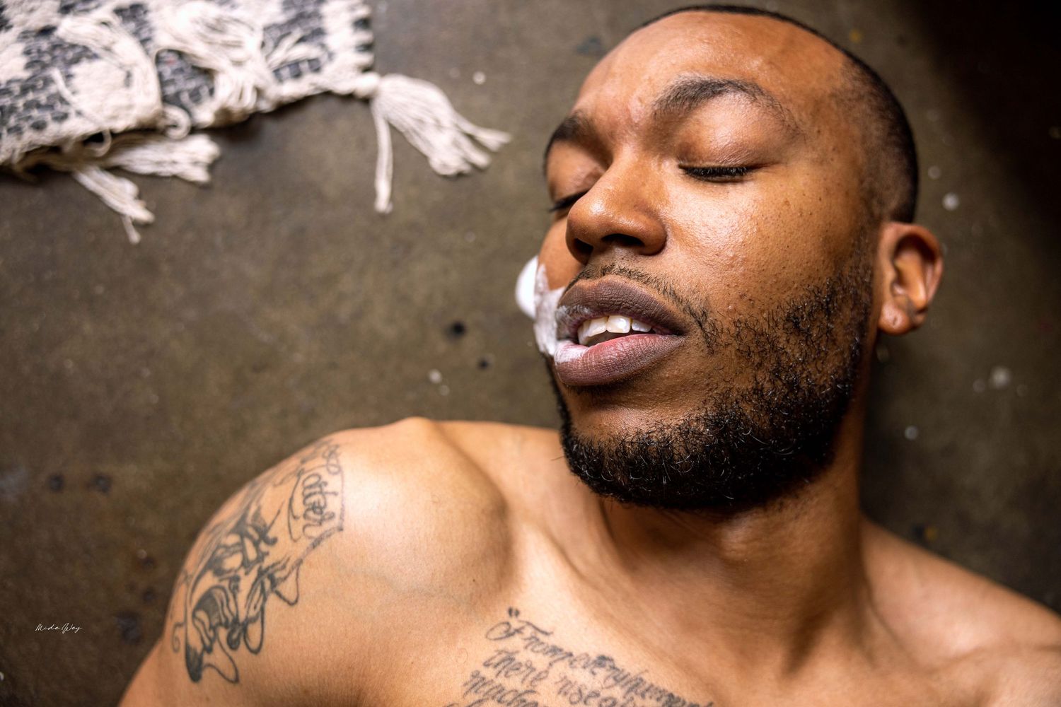 Artistic portrait showing closed eyes and smoke with visible tattoos.