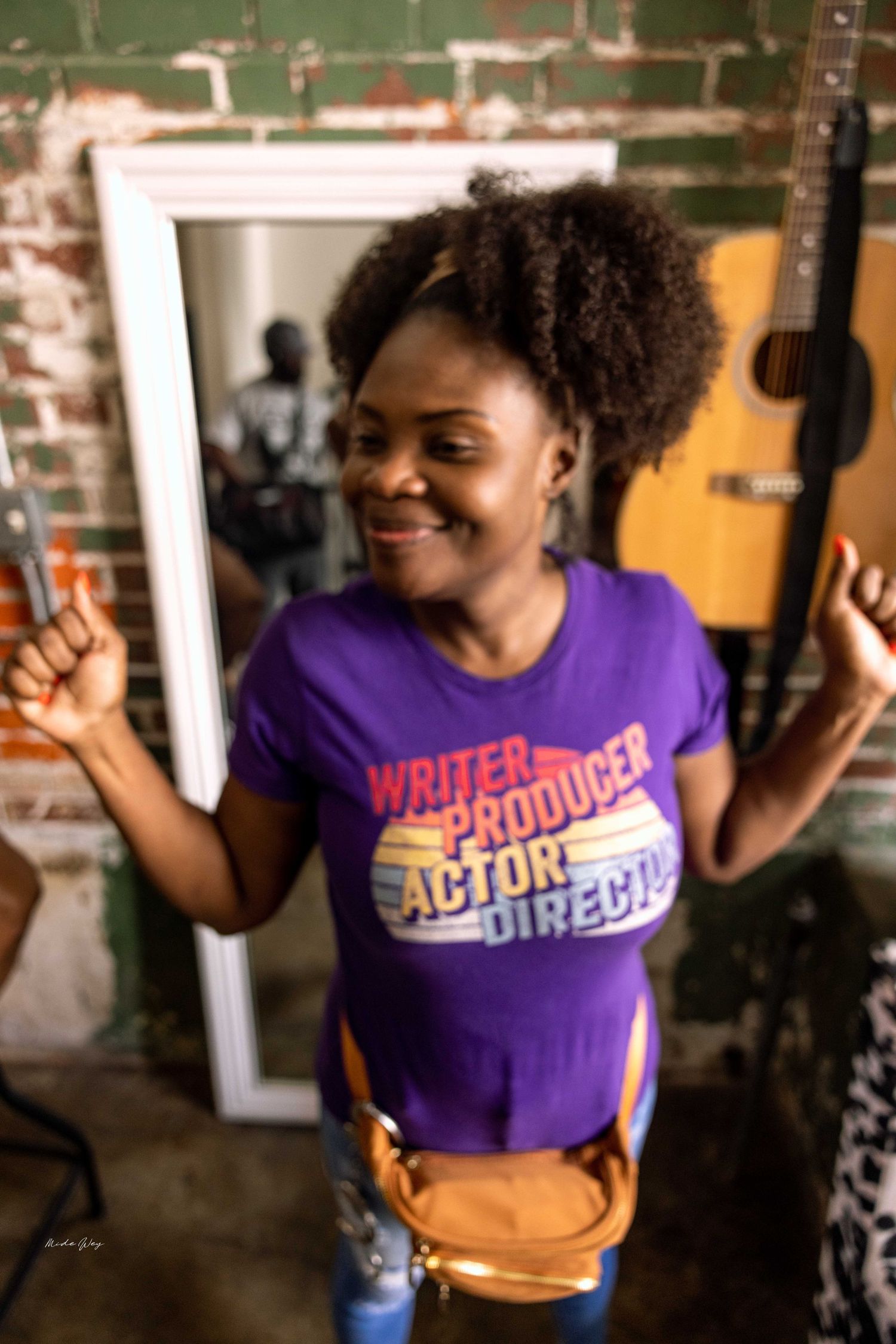 Creative video shoot featuring purple shirt and natural lighting against brick wall backdrop.