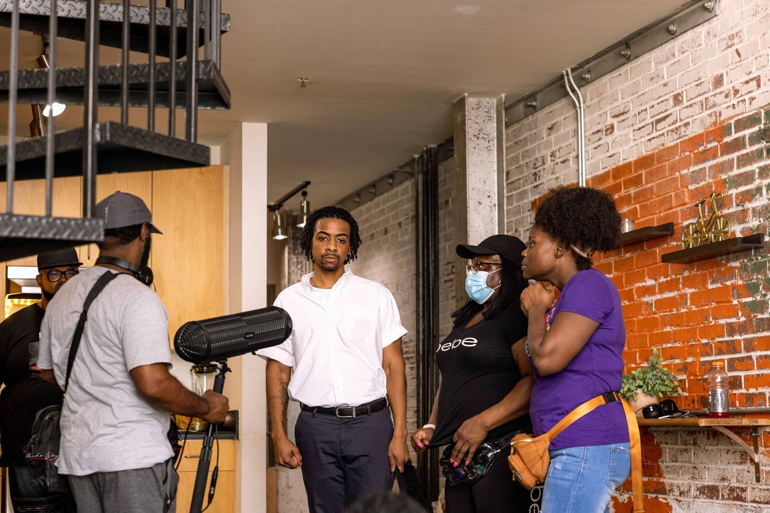 Production team filming with professional video equipment in a rustic studio with exposed brick walls.