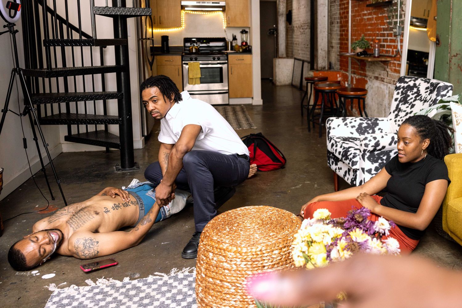 People relaxing in an industrial-style space with spiral staircase and brick walls.