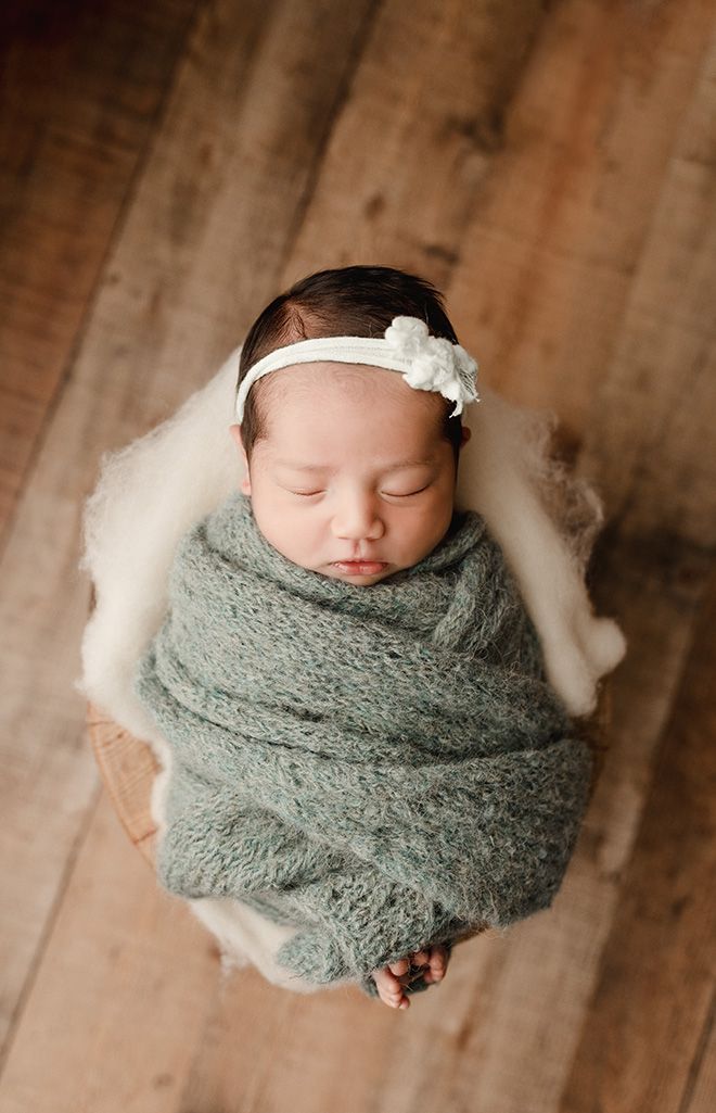 Eden Prairie newborn photographer | newborn-baby-wrapped-in-green-knitted-wrap-in-a-bucket-on-wooden-floor